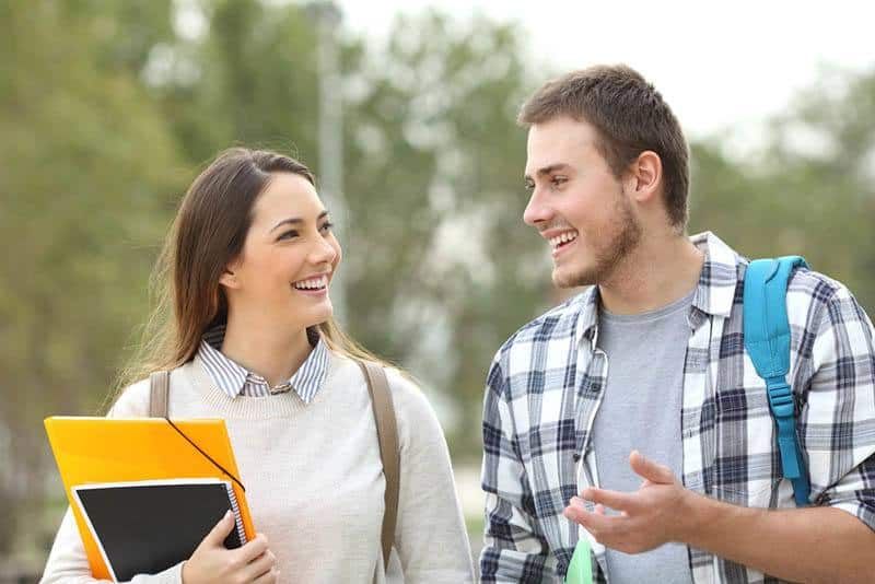 Zwei lächelnde College-Studenten unterhalten sich draußen