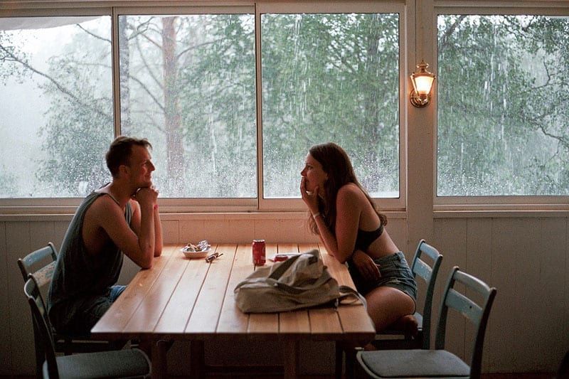 Mann und Frau unterhalten sich in einem Café, während es draußen regnet