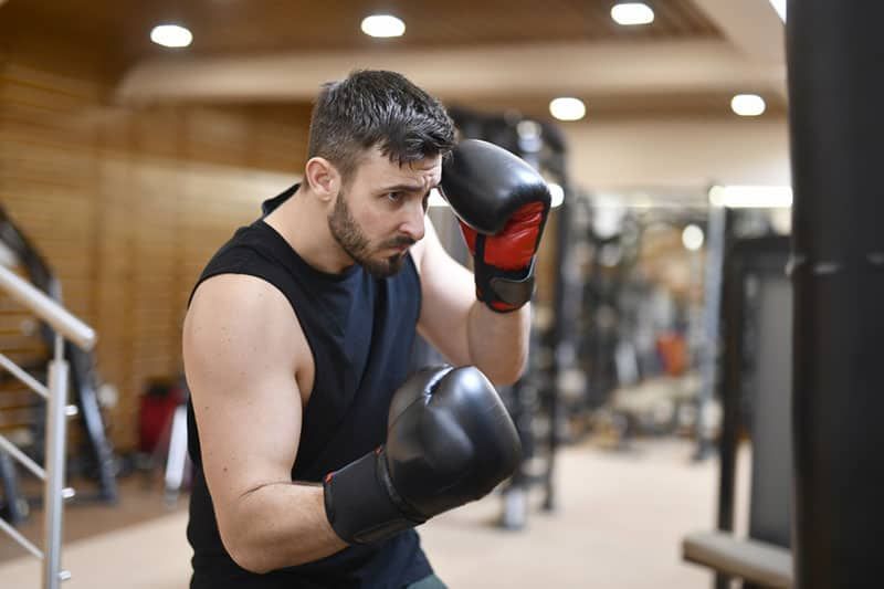 Mann mit Boxhandschuhen boxt in einem Fitnessstudio
