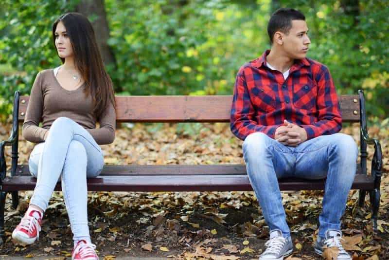 Junges verärgertes Paar sitzt auf einer Parkbank