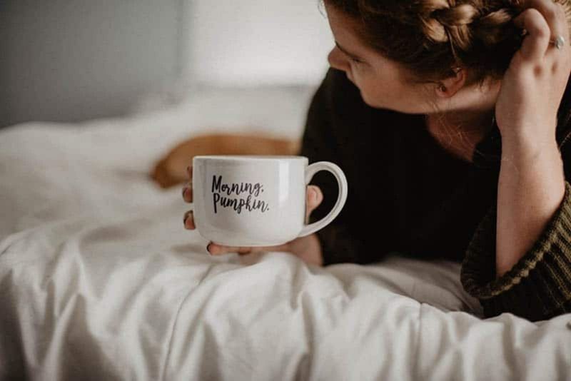 Frau trinkt ihren Morgenkaffee im Bett