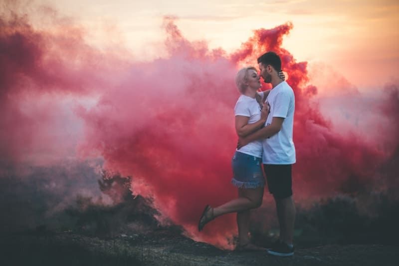 Paar umarmt sich neben rosa Rauch