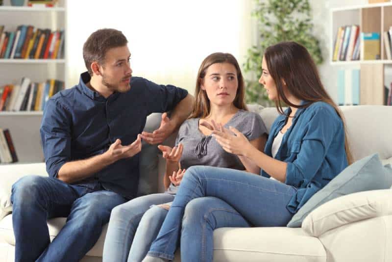 Drei freundliche Freunde unterhalten sich auf einer Couch im Wohnzimmer und sitzen am Haus