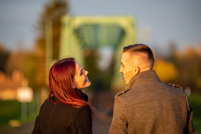 Mann und Frau lachen, während sie draußen stehen