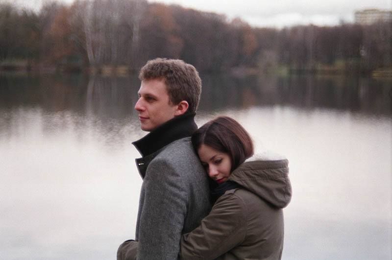 Frau umarmt Mann von hinten am See