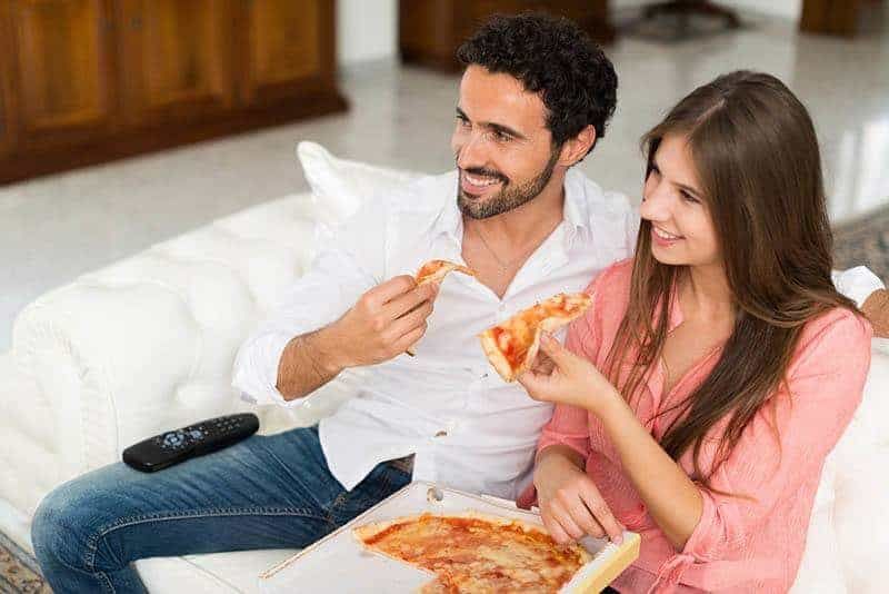 Paar isst Pizza, während es fernsieht