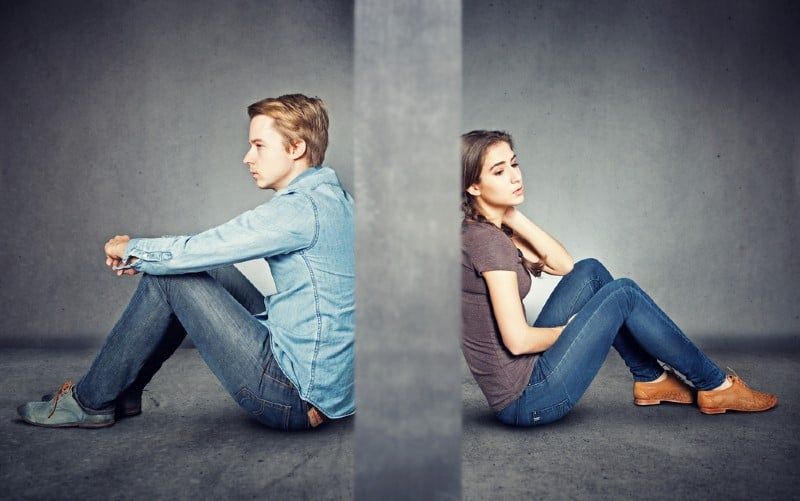 Graue Wand zwischen Mann und Frau, die auf dem Boden sitzen