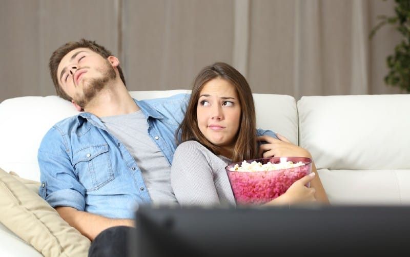 Mann schläft auf Couch neben Frau und schaut fern