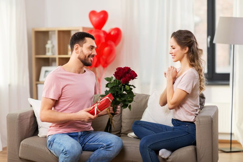 Mann überrascht Frau mit Geschenken und Rosen