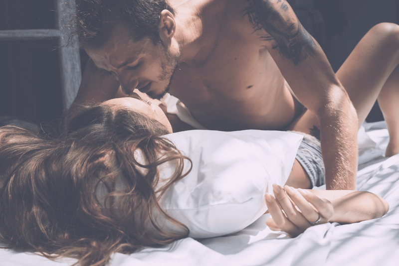 Ein Mann kuschelt mit einer Frau im Bett
