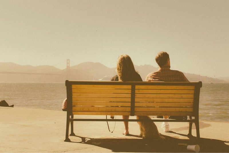 Mann und Frau sitzen auf einer Bank und schauen auf das Wasser