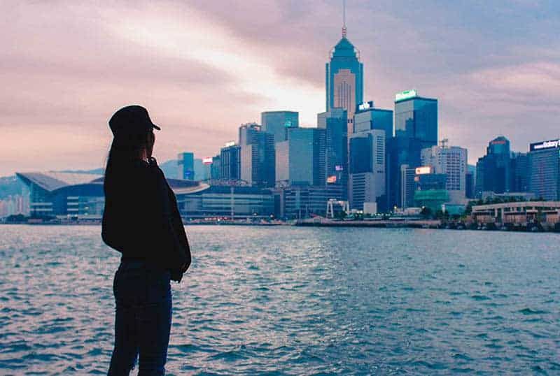 Frau mit Hut steht vor dem Meer