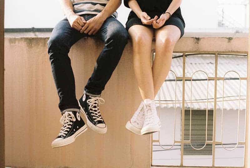 Mann und Frau tragen Converse All Star und sitzen nebeneinander