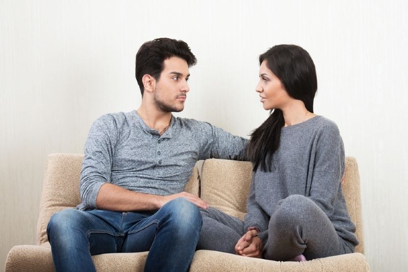 Mann und Frau unterhalten sich, während sie auf dem Sofa sitzen