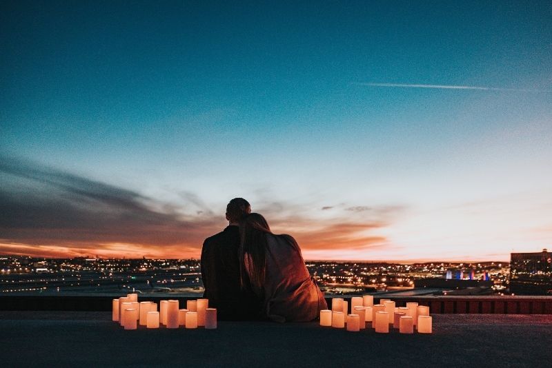 Mann und Frau sitzen auf dem Dach und schauen auf die Stadt