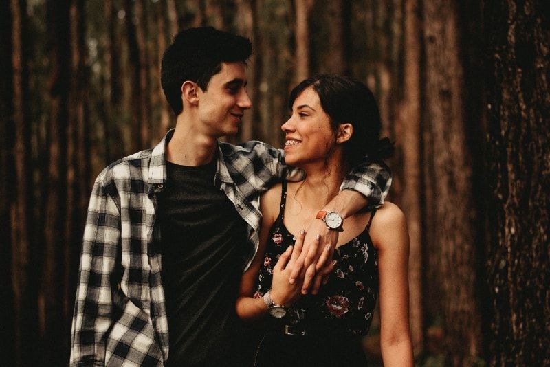 Mann und Frau umarmen sich, während sie im Wald stehen