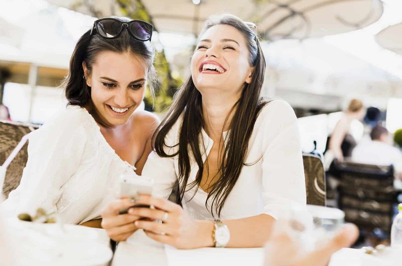 Zwei junge Frauen schauen lachend auf das Telefon
