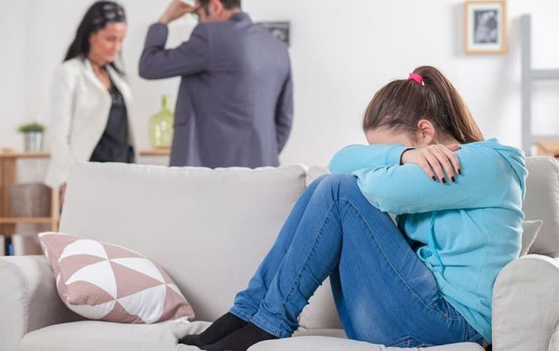 Familienszene mit streitenden Eltern und dem Kind auf dem Sofa