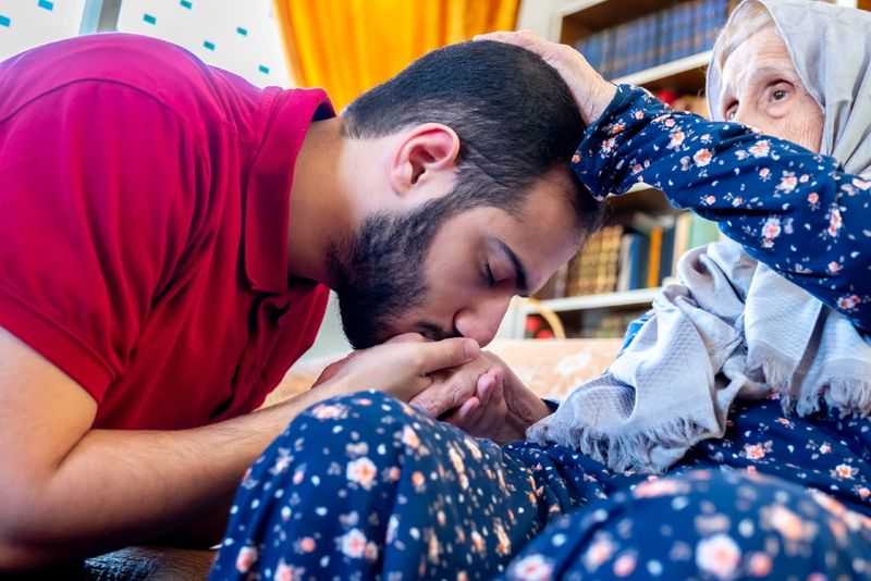 Arabischer muslimischer Mann im roten T-Shirt, der Großmutter küsst