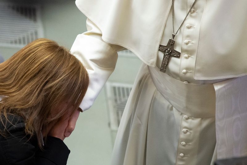 Frau in schwarzer Jacke küsst Papst