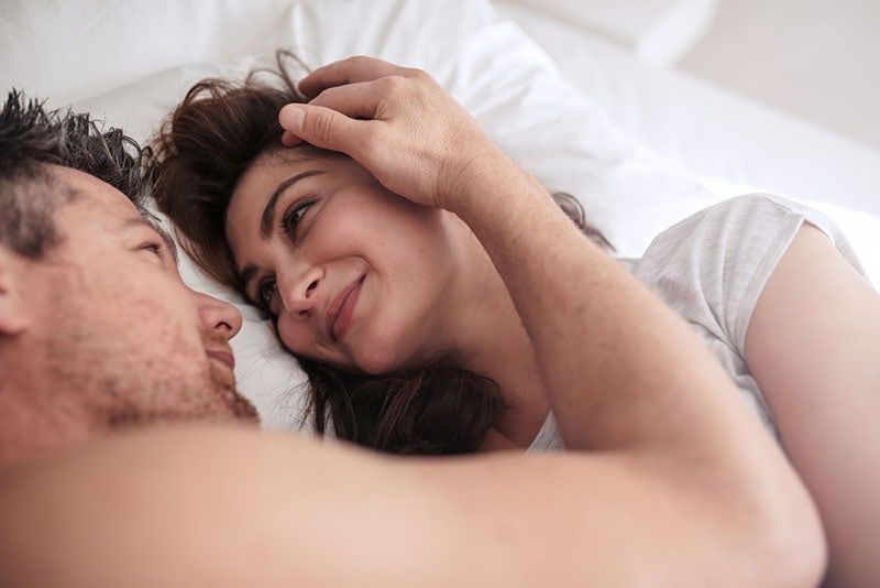 Mann kuschelt mit Frau im Bett