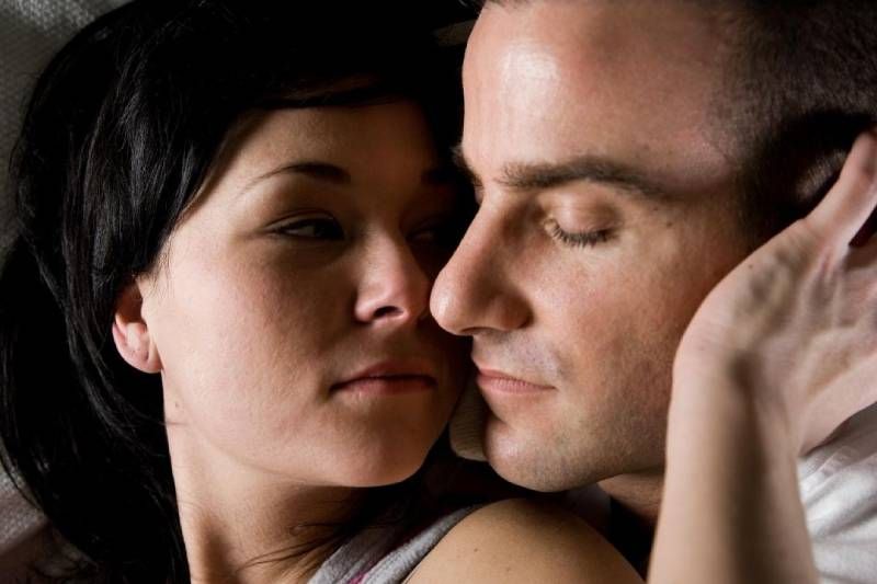 Paar kuschelt im Bett, Frau berührt Mann