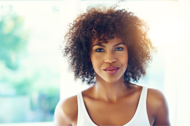 ein Porträt einer attraktiven schwarzen Frau in einem weißen Unterhemd