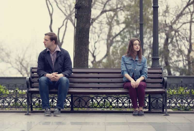 distanziertes Paar sitzt auf der Parkbank