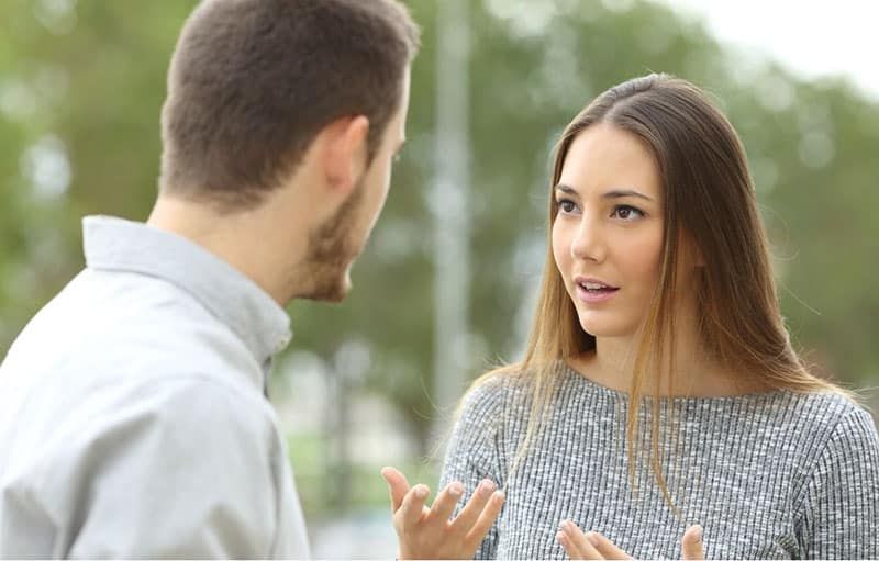 Paar streitet sich im Freien mit einer Frau, die ein graues Oberteil trägt
