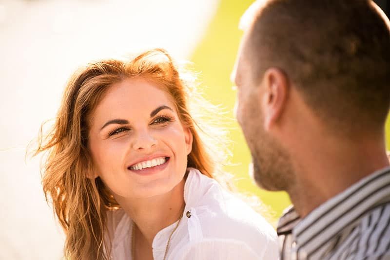 Lächelnde junge Frau, die ihrem Mann bei einem Date im Freien in die Augen blickt