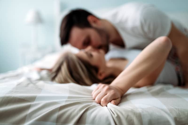 Mann und Frau küssen sich, während sie im Bett liegen