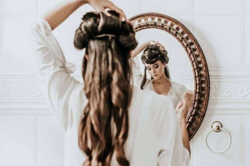 Frau im weißen Kleid vor dem Spiegel