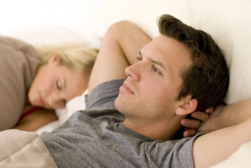 besorgter Mann in tiefen Gedanken, während Frau schläft