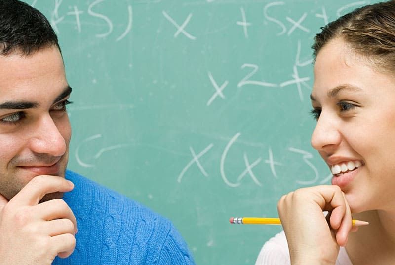 Mann und Frau starren einander scharf an der Tafel an, auf der mathematische Gleichungen geschrieben sind