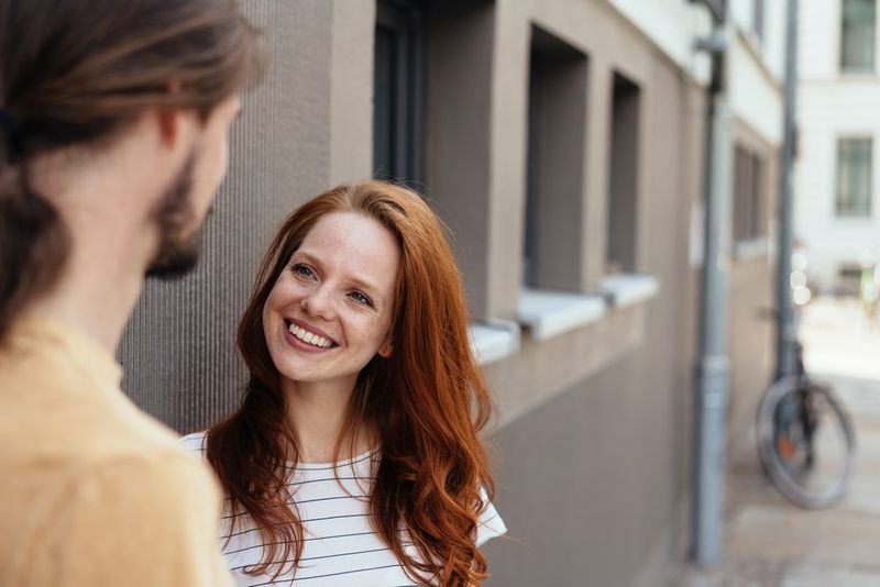 Ein rothaariges lächelndes Mädchen auf der Straße, das mit einem Mann spricht