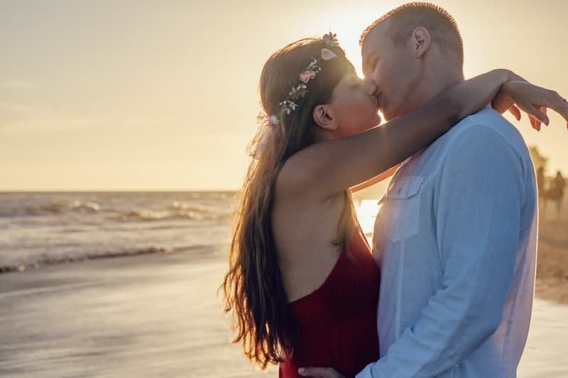glückliches Paar, das sich bei Sonnenuntergang küsst
