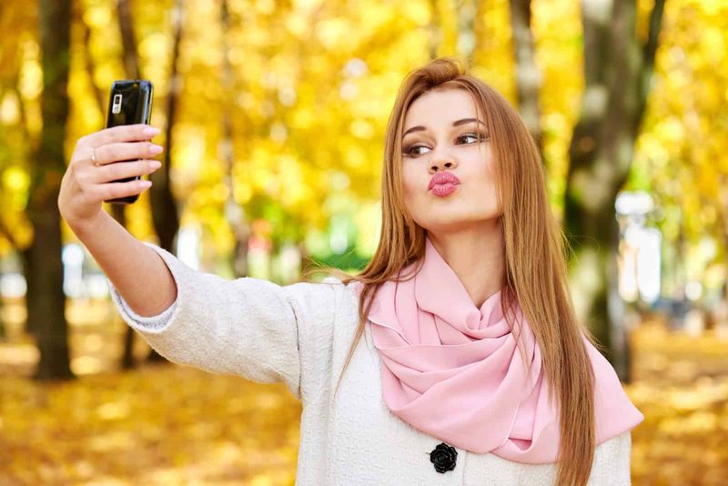 Frau macht ein Entengesicht, während sie ein Selfie macht
