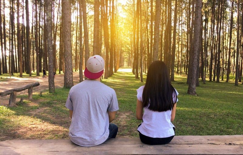 junges Paar sitzt auf einer Bank mitten im Wald