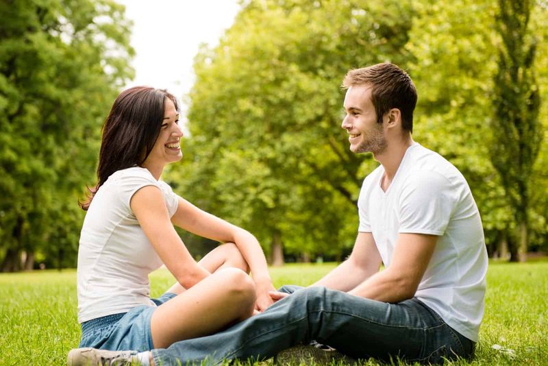Ein Mann und eine Frau sitzen im Gras und unterhalten sich
