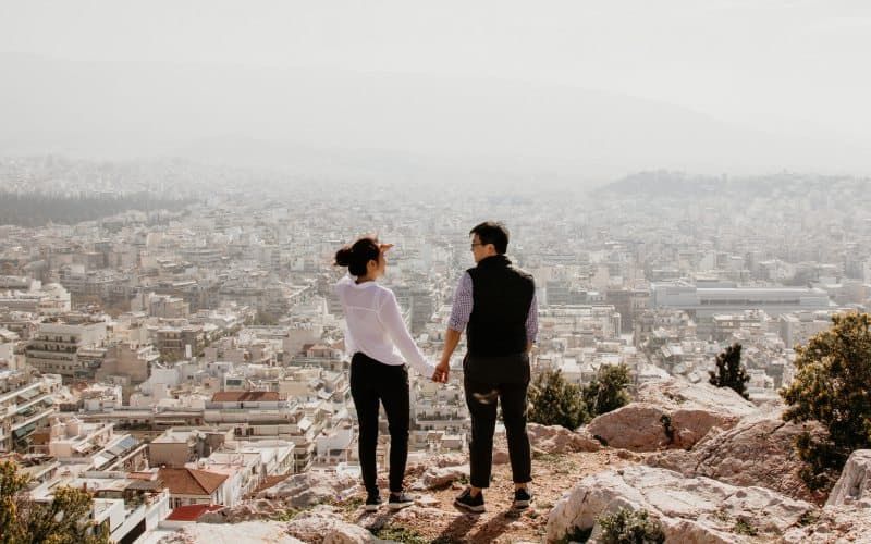 Mann und Frau halten ihre Hände zusammen, während sie oben auf einer Klippe stehen