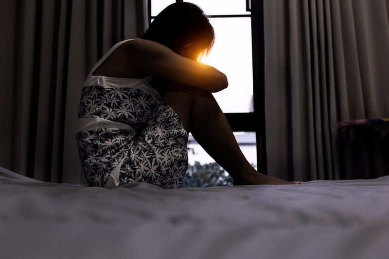 Eine traurige Frau im Nachthemd sitzt auf dem Bett
