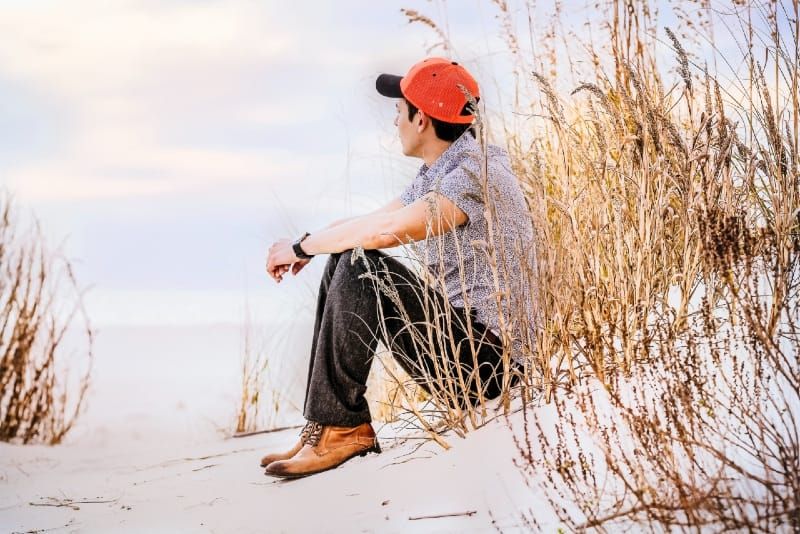 Mann sitzt auf Sand mit Weizen und sieht tagsüber richtig aus