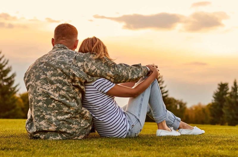 Militärpaar sitzt draußen und umarmt sich