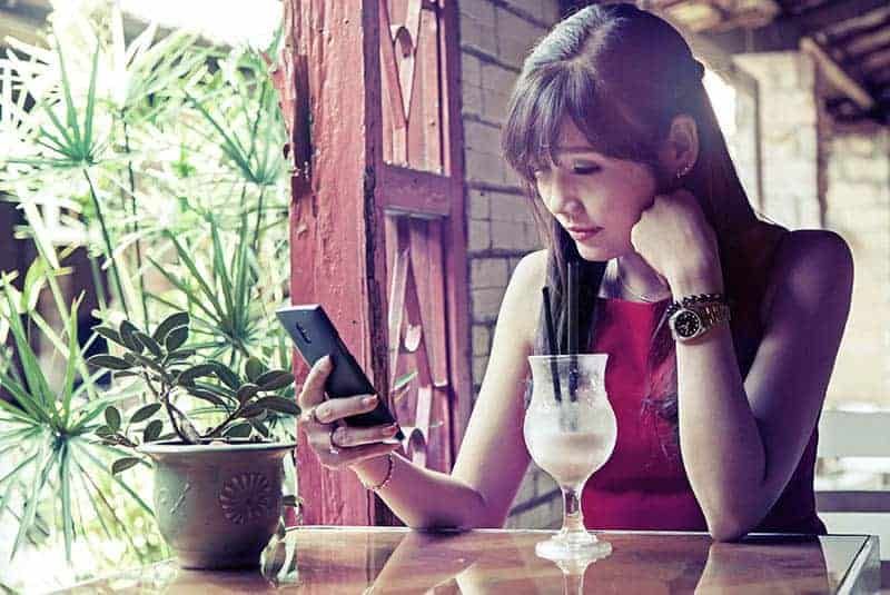 Asiatische Frau tippt im Café auf ihrem Telefon