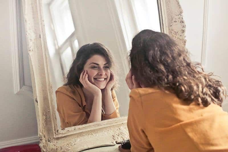 lächelnde Frau, die in den Spiegel schaut