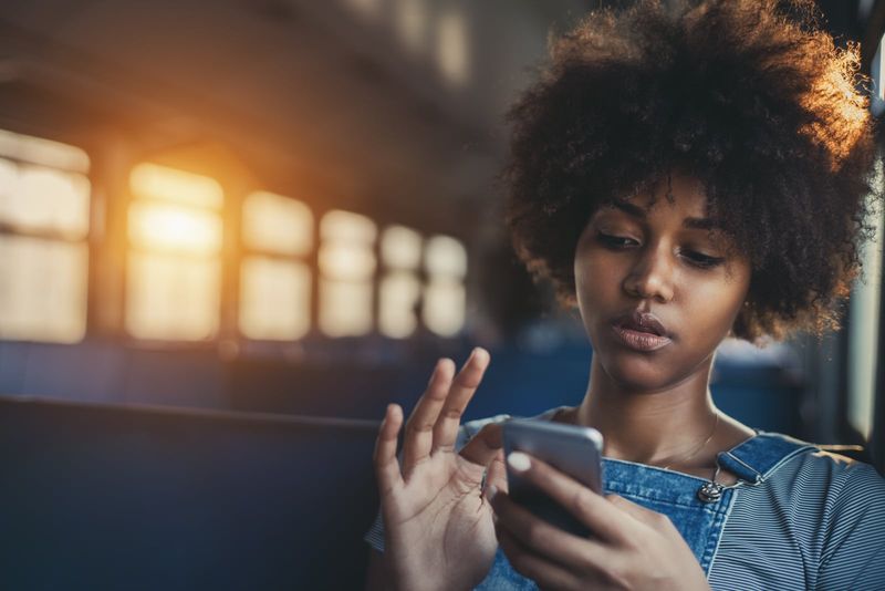 Mädchen, das Smartphone benutzt, während es allein in der S-Bahn sitzt
