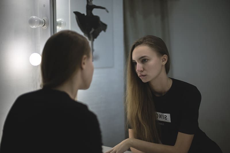 Junge Frau, die den Spiegel betrachtet