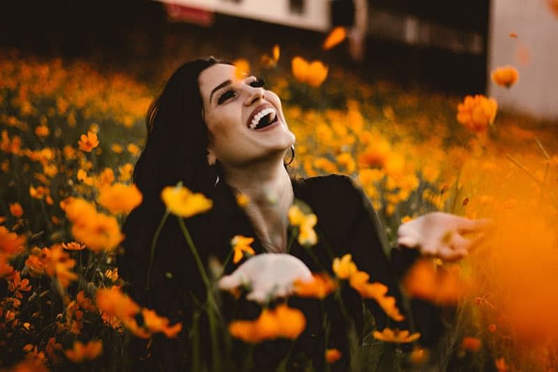 glückliche Frau, die auf dem Blumenfeld steht
