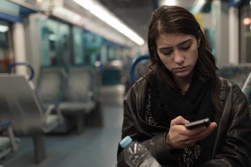 Frau sitzt im Zug und schaut auf ihr Telefon