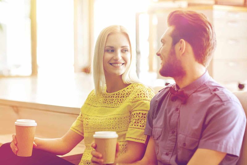 Eine schöne blonde Frau sitzt neben einem Mann und trinkt Kaffee